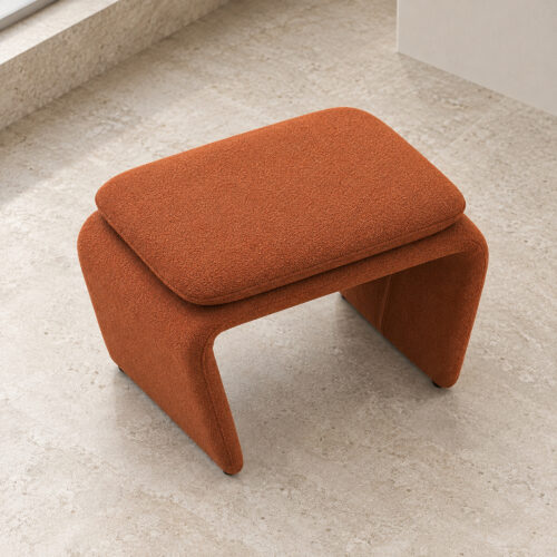Rylan Camel Fabric Footstool with Curved Upholstered Supports — high view on stone flooring